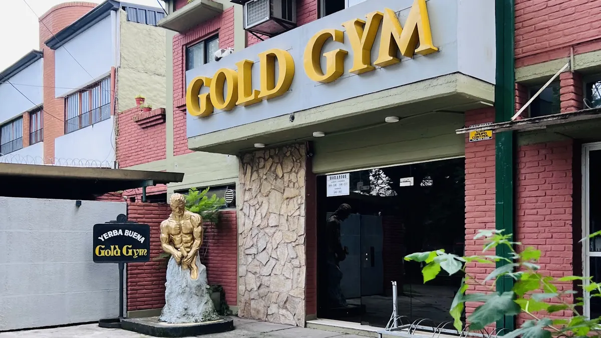 Frente de Gold Gym con el cartel dorado sobre la entrada
